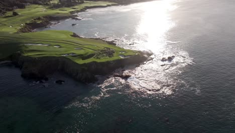 Vista-Aérea-Del-Icónico-Hoyo-7-Junto-Al-Mar-En-Los-Campos-De-Golf-De-Pebble-Beach-Mientras-El-Sol-Se-Refleja-En-El-Océano-Pacífico