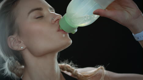 Sport-woman-drinking-water-from-fitness-bottle-on-black-background