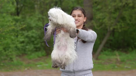 mujer sosteniendo un perro maltés en un parque