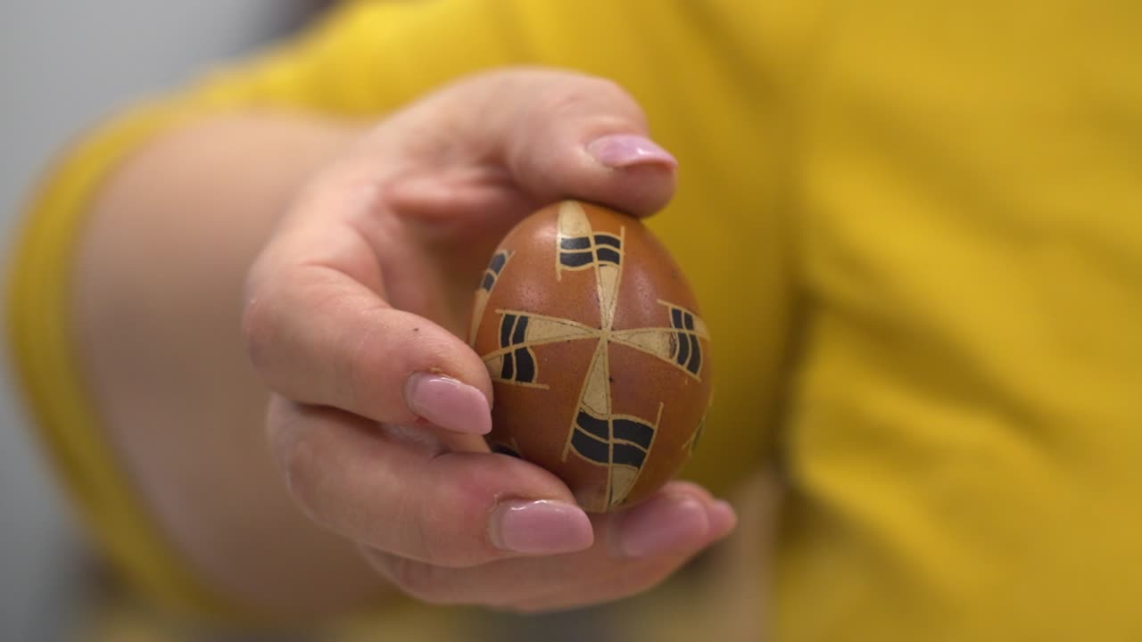 A hand holds a traditional Hungarian Easter egg with geometric wax patterns