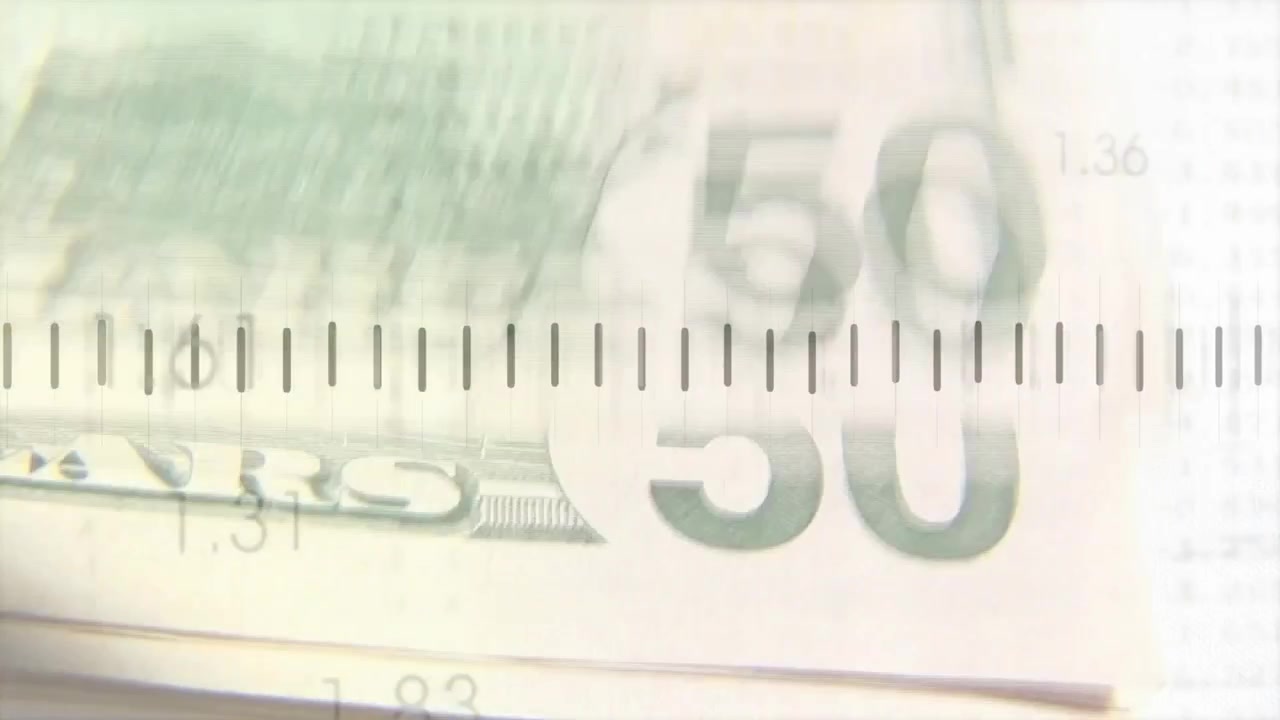 La telecamera si sposta su una pila di 50 banconote, un grafico frastagliato che sale e scende, etichette numeriche che mostrano le tendenze.