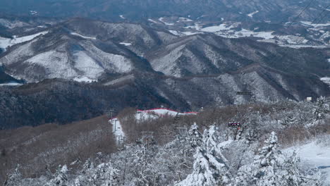 skiers travel on ski chair lift towards balwangsan mountain and daegwallyeong mountains chain valley top down view, gangwon-do - aerial view