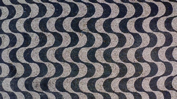 Top down aerial drone flight over the black and white wave cobblestone mosaic of Largo de Sao Sebastiao plaza, Portuguese pavement pattern filling the frame, abstract graphic texture, Manaus, Brazil.