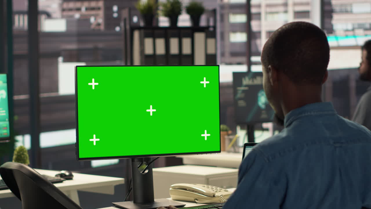 현대적 인 사무실 에서 녹색 스크린 모니터 를 보고 있는 사업가