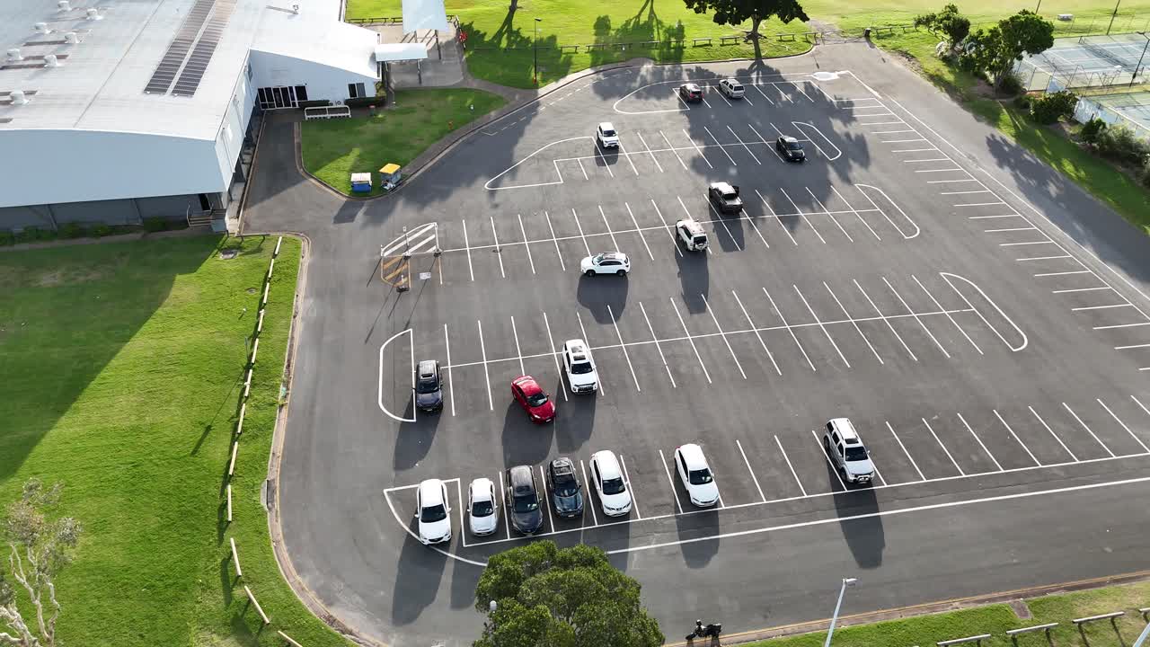 Drone footage captures cars maneuvering in a sunlit parking lot at Gold Coast Performance Centre