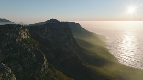 Vorwärts-Fliegen-Entlang-Der-Felskante-über-Der-Meeresküste.-Erstaunliche-Landschaftskulisse-Gegen-Helle-Sonne-Bei-Sonnenuntergang.-Kapstadt,-Süd-Afrika