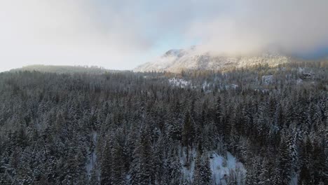 Cinematic-Scene-of-Snow-Covered-Forests-with-Majestic-Mountains-Surrounded-by-Clouds-during-Golden-Hour-in-the-Thompson-Nicola-Region,-BC,-Canada