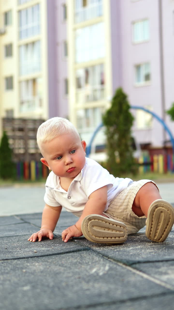 Un bambino disegna con il gesso sull'asfalto durante una passeggiata. Un bambino disegna con il gesso. Abbigliamento estivo per bambini.
