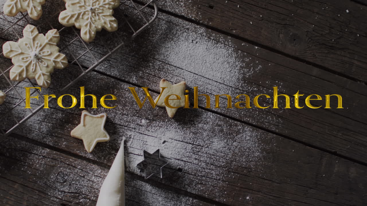 Schriftzug „Frohe Weihnachten“ in Gold über Schneeflocken-Weihnachtsplätzchen auf dunklem Holzhintergrund