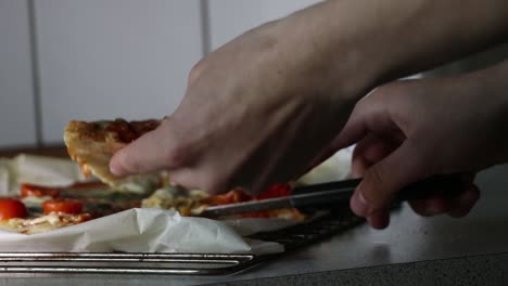 hand cutting a slice of pizza