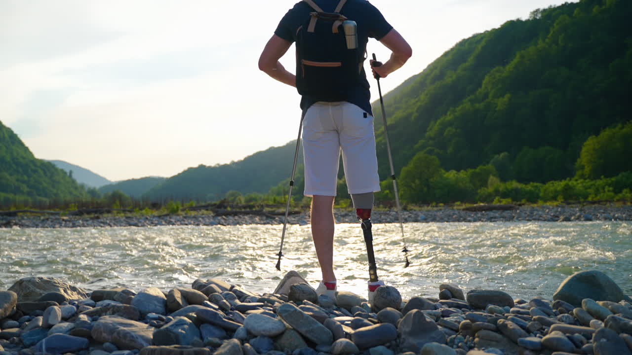 인공 다리를 가진 남자가 강 의 산에서 하이킹을 하고 있다