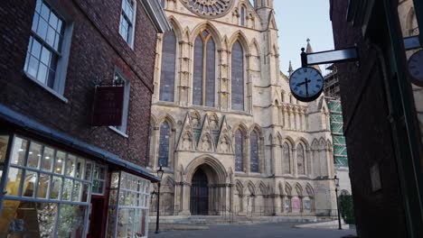 slow wide reveal shot of york minster cathedral at sunrise through the narrow cobbled streets of york