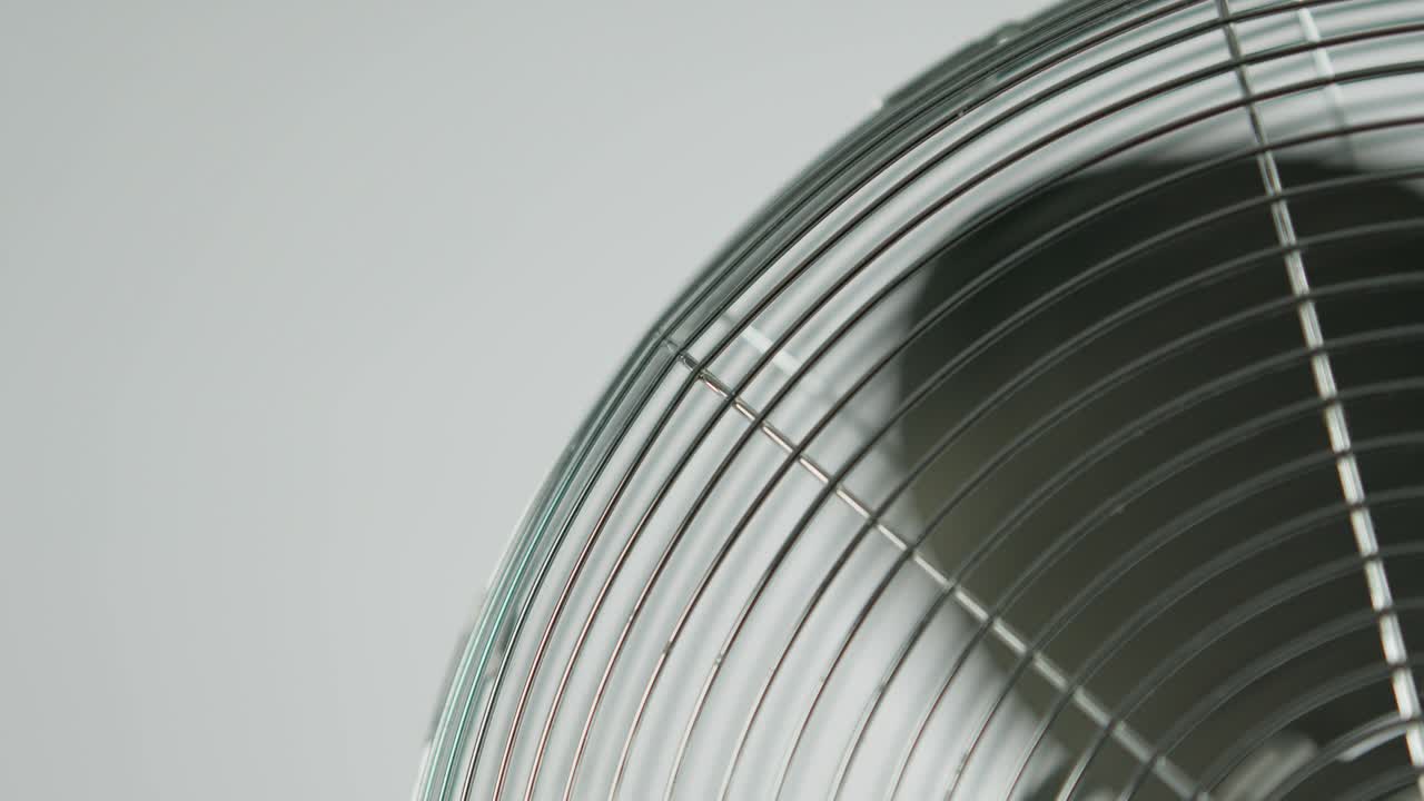 백색 배경 앞의 금속 환기기의 검은색 팬 블레이드가 느려지는 느린 동작