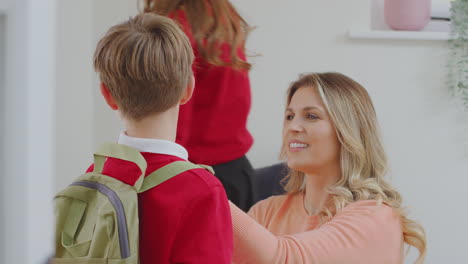 padres ayudando a los niños en uniforme a prepararse para salir de casa para ir a la escuela