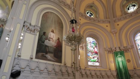 Elegant-gold-chandelier-hanging-in-the-sanctuary-with-beautiful-painting-of-Jesus-and-a-stain-glass-window-in-the-background-at-St