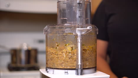 turning on the food processor full of cashews and roasted red peppers to grind them into a savory dip - isolated