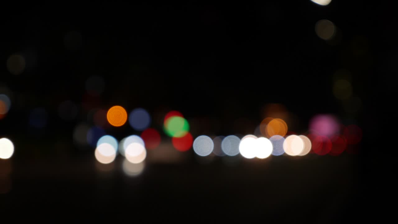 hermoso bokeh brillante en el fondo oscuro borroso por la noche. el redondo bokeh colorido brilla de las luces de los coches en la calle de la ciudad. fuera de foco con borroso. luces de la ciudad sin enfoque. bokeh de tráfico. concepto abstracto