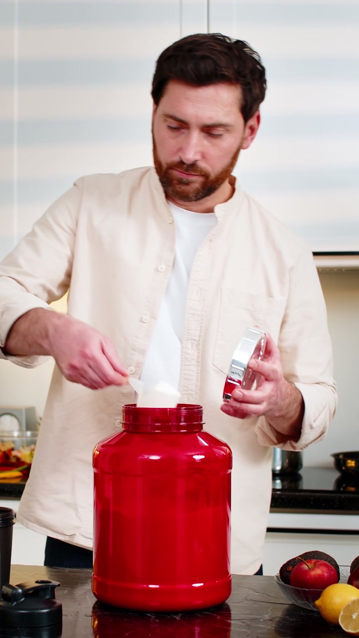 Uomo di mezza età che prepara uno shake proteico con il latte in cucina per una dieta sana, l'allenamento fitness e la nutrizione.