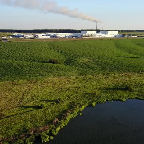 countryside farm with lake. view of a factory in the middle of a green field