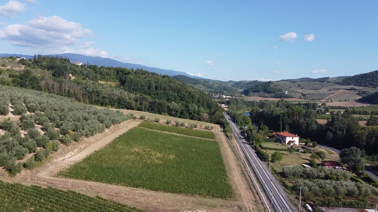 campo italiano campos verdes y viñedos junto a las vías del tren en un día soleado y tranquilo, cielo azul claro
