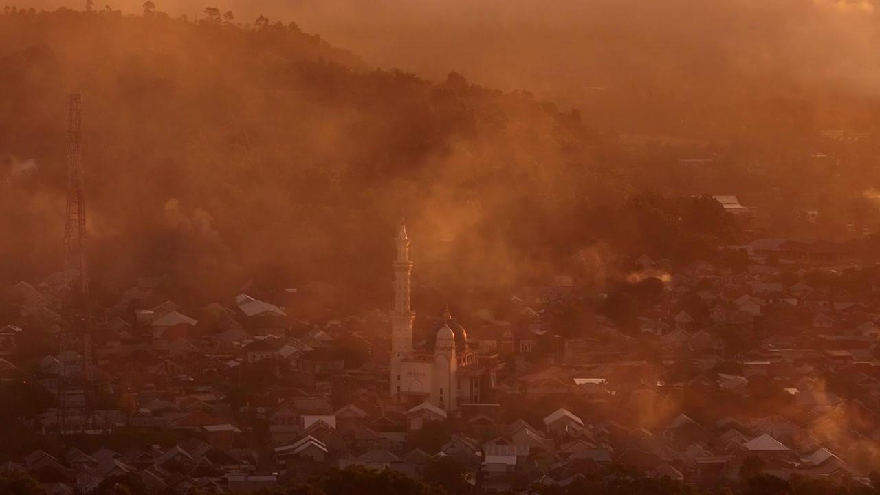 Una etérea niebla del amanecer se desplaza sobre el pueblo de Sembalun bañado en la luz dorada de la mañana, órbita aérea de establecimiento de la torre de la iglesia mezquita, Masjid Ittihadul Islam Lawang