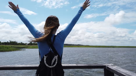 cinematic shot of a woman who raises her arms before the majesty of the landscape