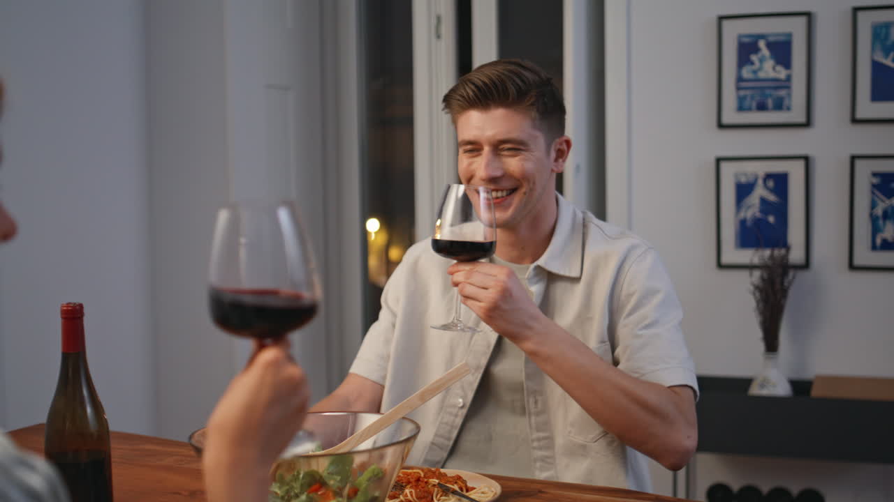 Happy man toasting wine at home closeup. Cheerful husband enjoying conversation