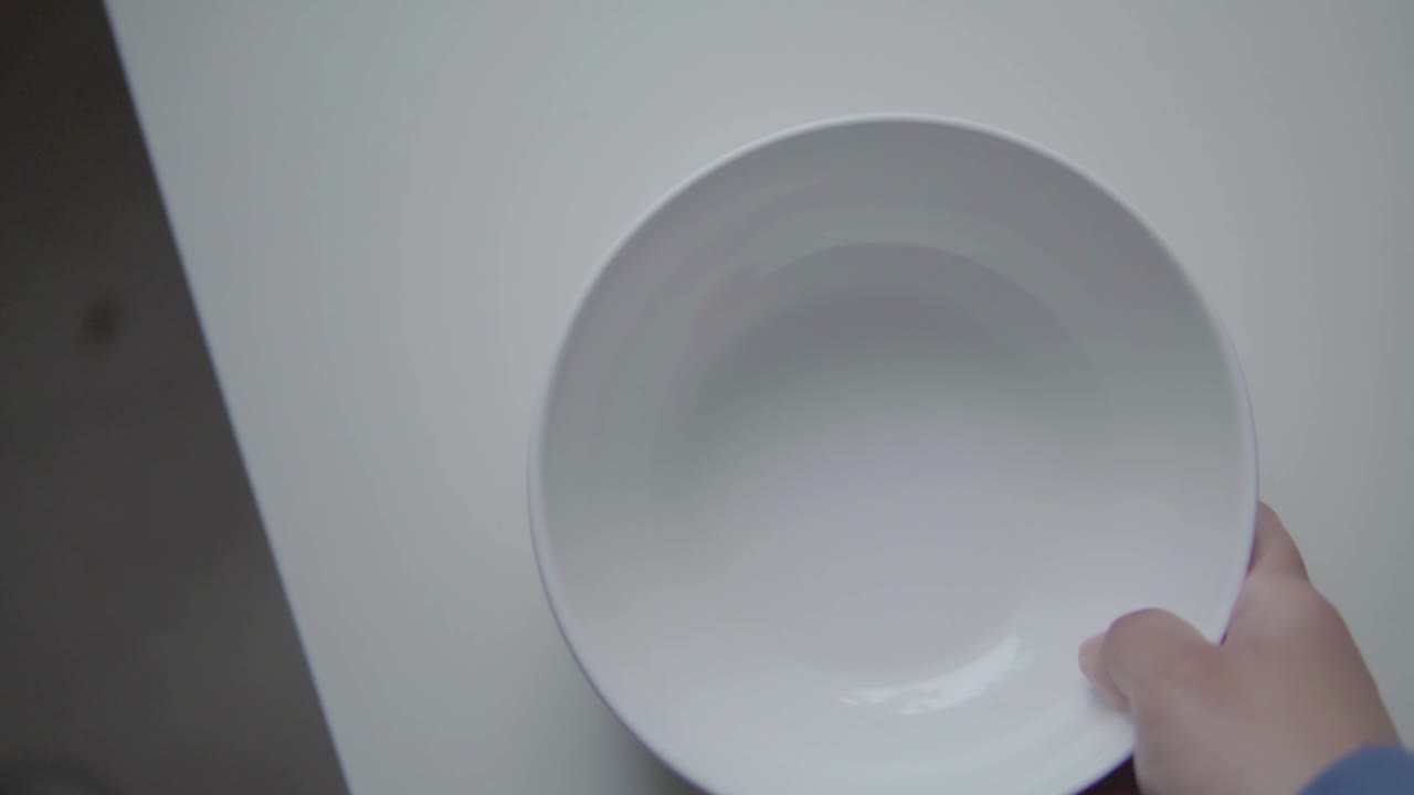 Hand putting white bowl on table