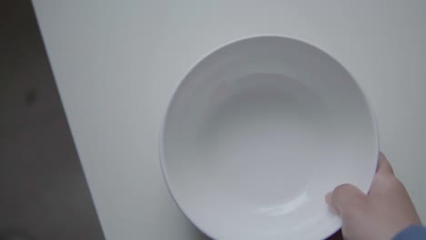 hand putting white bowl on table