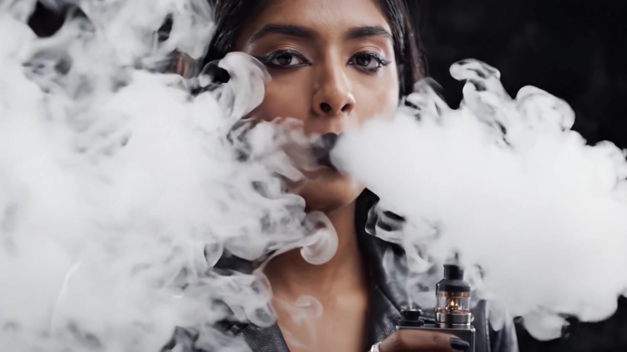 A Mysterious Figure Shrouded in Vapor: The Allure of Modern Vaping Culture Captured in Two Striking Frames of Ethereal Smoke and Stylish Presentation