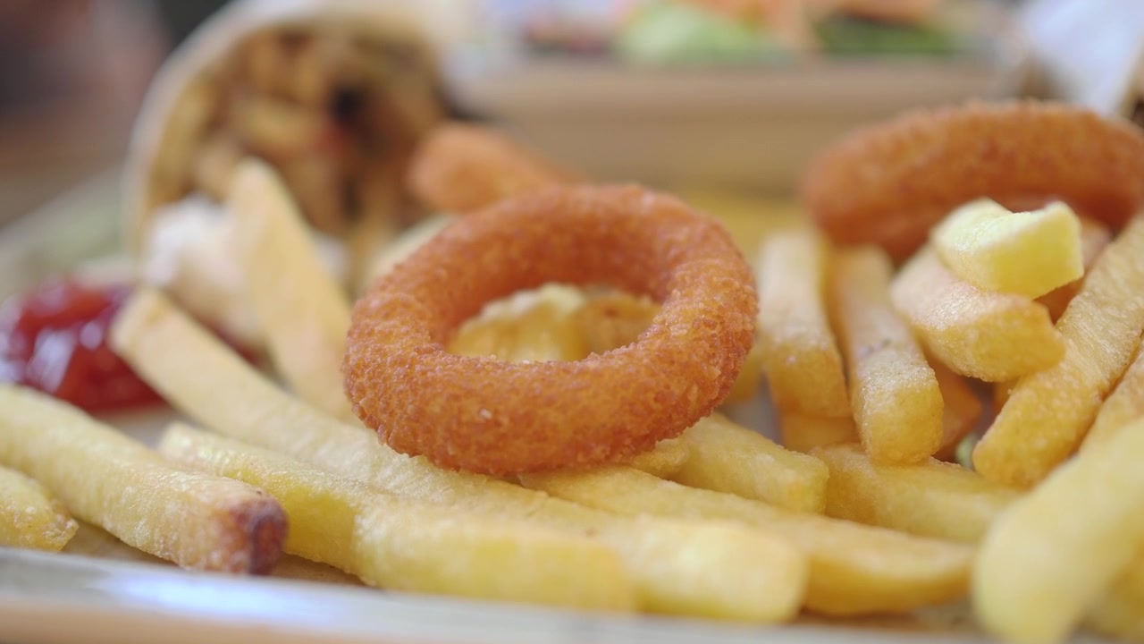 Close-up de batatas fritas crocantes e anéis de cebola em um prato