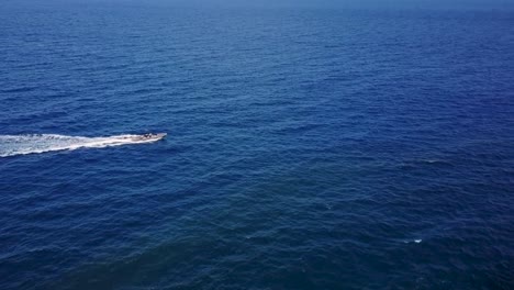 flying next to a speed boat on the blue ocean