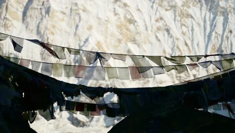 close up prayer flags in snowy mountains in nepal, colorful tibetan prayer flags on blue sky sunny day in the snowcapped himalayas in annapurna, colourful buddhism flags in nature
