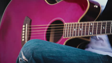 shot of a woman playing a red guitar outside.