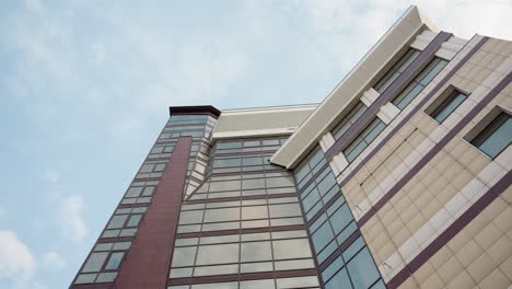 close view of a modern city building with a sleek glass facade and architectural design, the side perspective of the building's structure against a backdrop of a clear blue sky