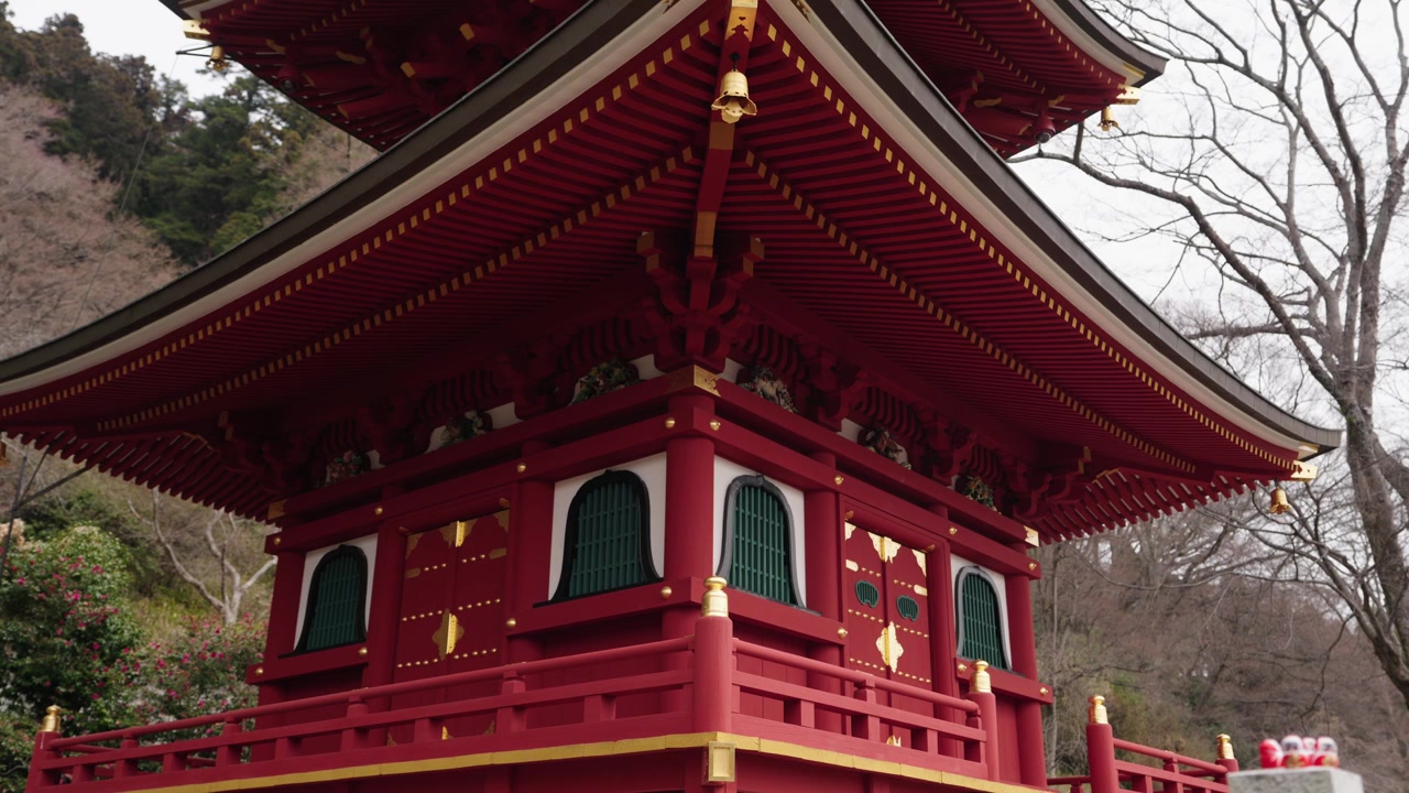 Udsmykket rød lak to-etagers pagode med gulddetaljer og klokker ved Katsuoji, Osaka
