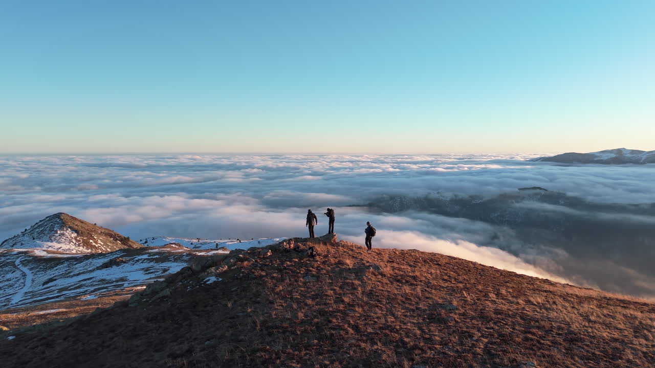 Hikers on a mountain summit at sunrise, enjoying a panoramic cloud view