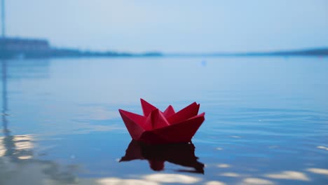 woman's hand putting paper boat on the water. beautiful summer sunset. paper boat. origami.