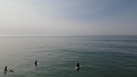 un tiro terminado rozando las olas del océano lejos de la orilla hacia los surfistas sentados esperando una ola