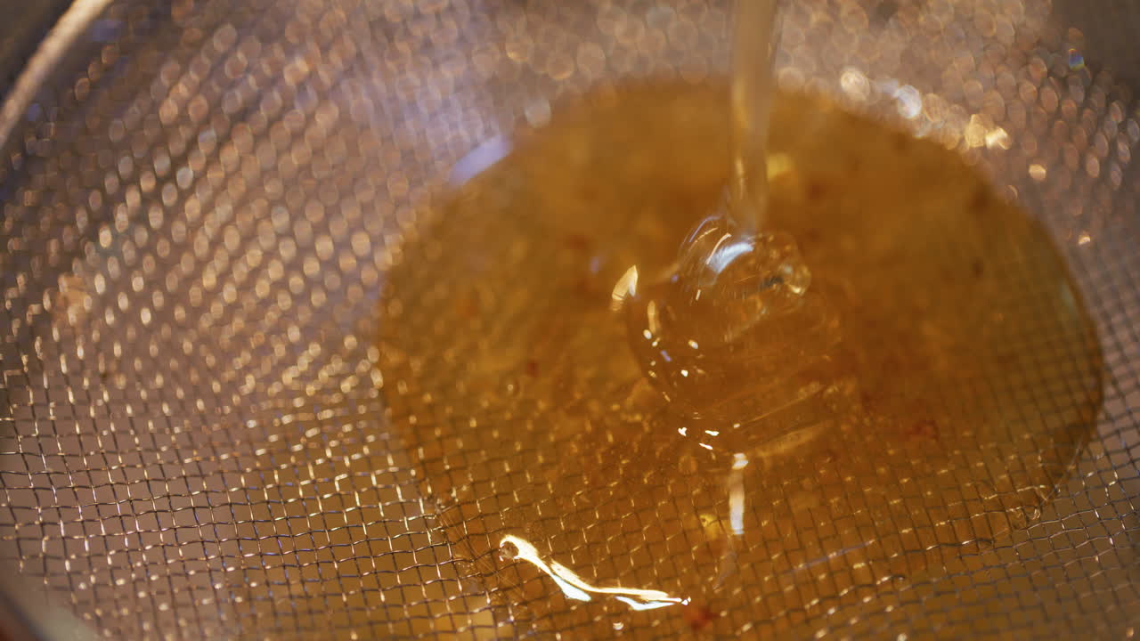 Miele dorato filtrato attraverso un colino