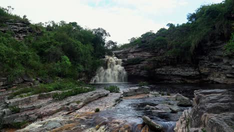 inclinándose hacia arriba, una toma de 4k que revela la impresionante cascada del pozo del diablo rodeada de follaje y rocas en un día lluvioso nublado en el famoso parque nacional chapada diamantina en el noreste de brasil