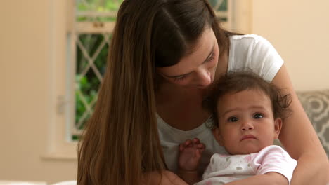 madre con un bebé lindo sentado en la cama