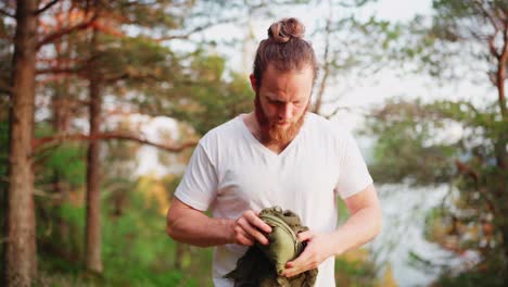 male hiker untying hammock in the woodland