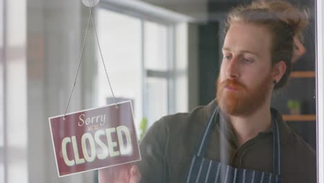 caucasian male hairdresser turning shop sign to open on door of hair salon, in slow motion