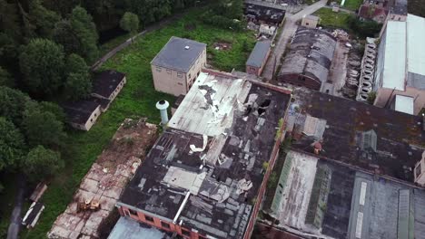 drone flight over destroyed roof top of old abandoned socialist factory in the woods in europe