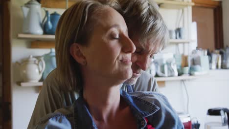 senior caucasian couple wearing aprons and embracing before cooking in kitchen