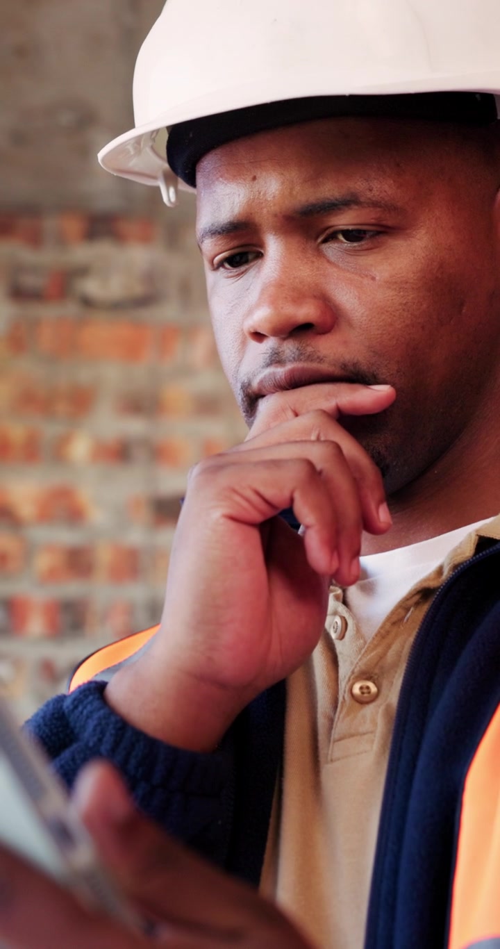 Construction Worker Reviewing Plans on Tablet at Building Site