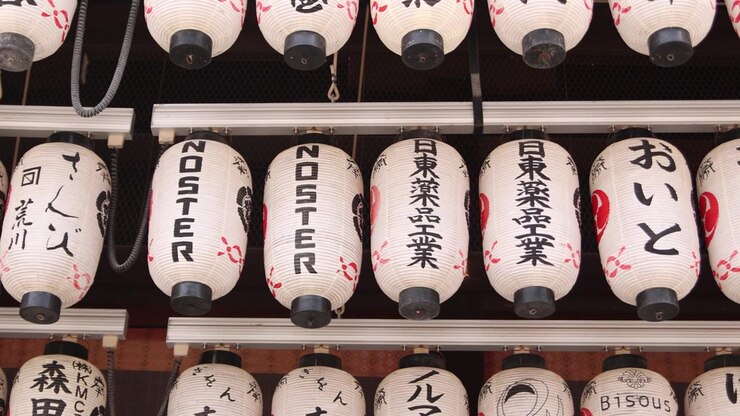 Vista ravvicinata di file di lanterne di carta tradizionali al Santuario Yasaka nel quartiere Gion di Kyoto, con calligrafia giapponese e dettagli decorativi del santuario associati al culto shintoista.