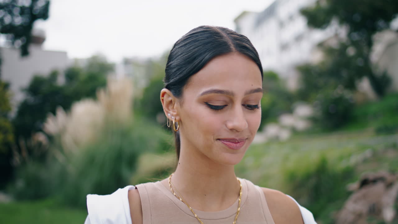 retrato de una mujer hermosa sonriendo cámara en el jardín verde. modelo hispano caminando