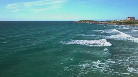 Aerial-side-shot-of-surfers-waiting-for-a-wave-at-Fistral-beach,-Newquay,-Cornwall